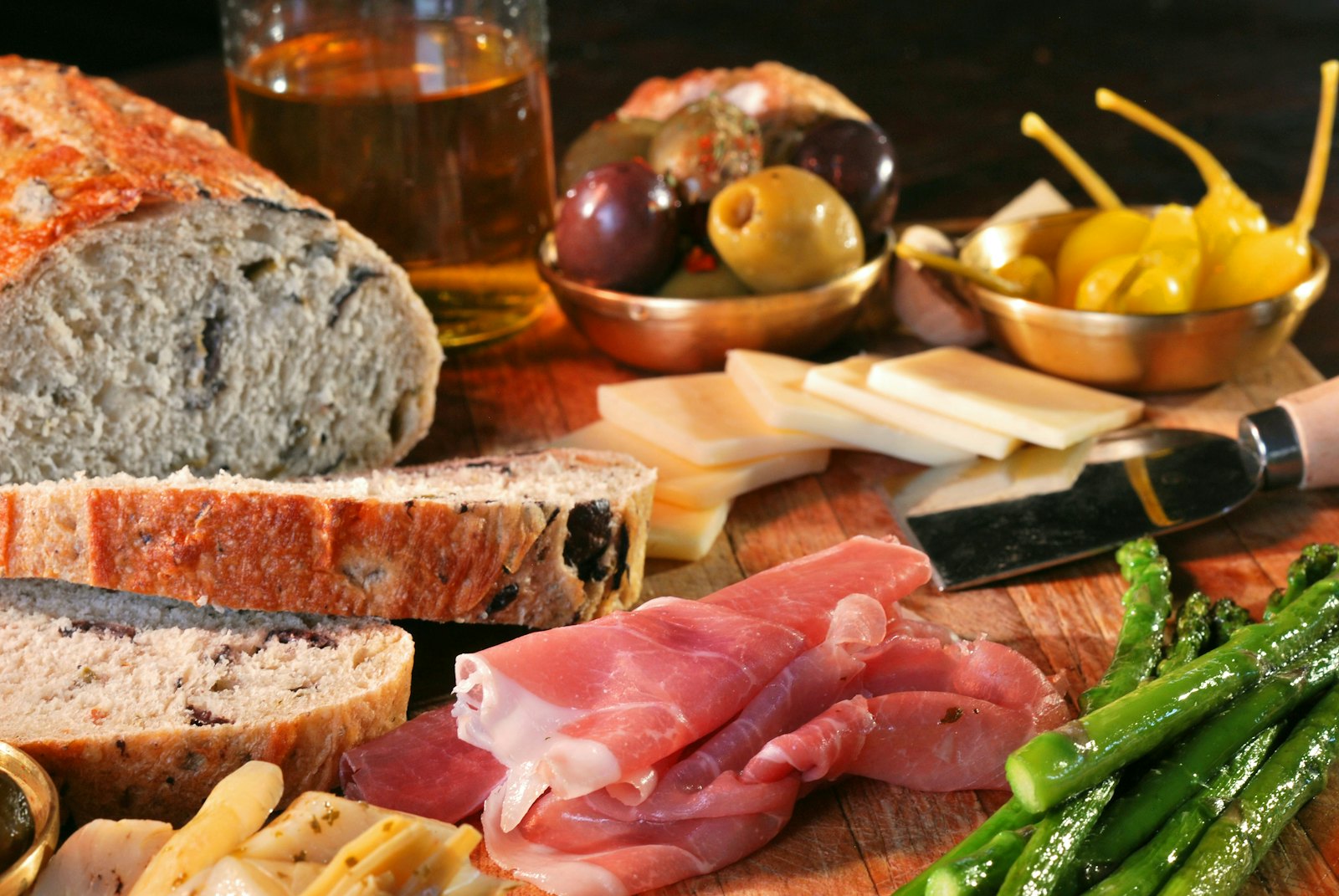 Brot, Schinken und Antipasti auf einem Holzbrett